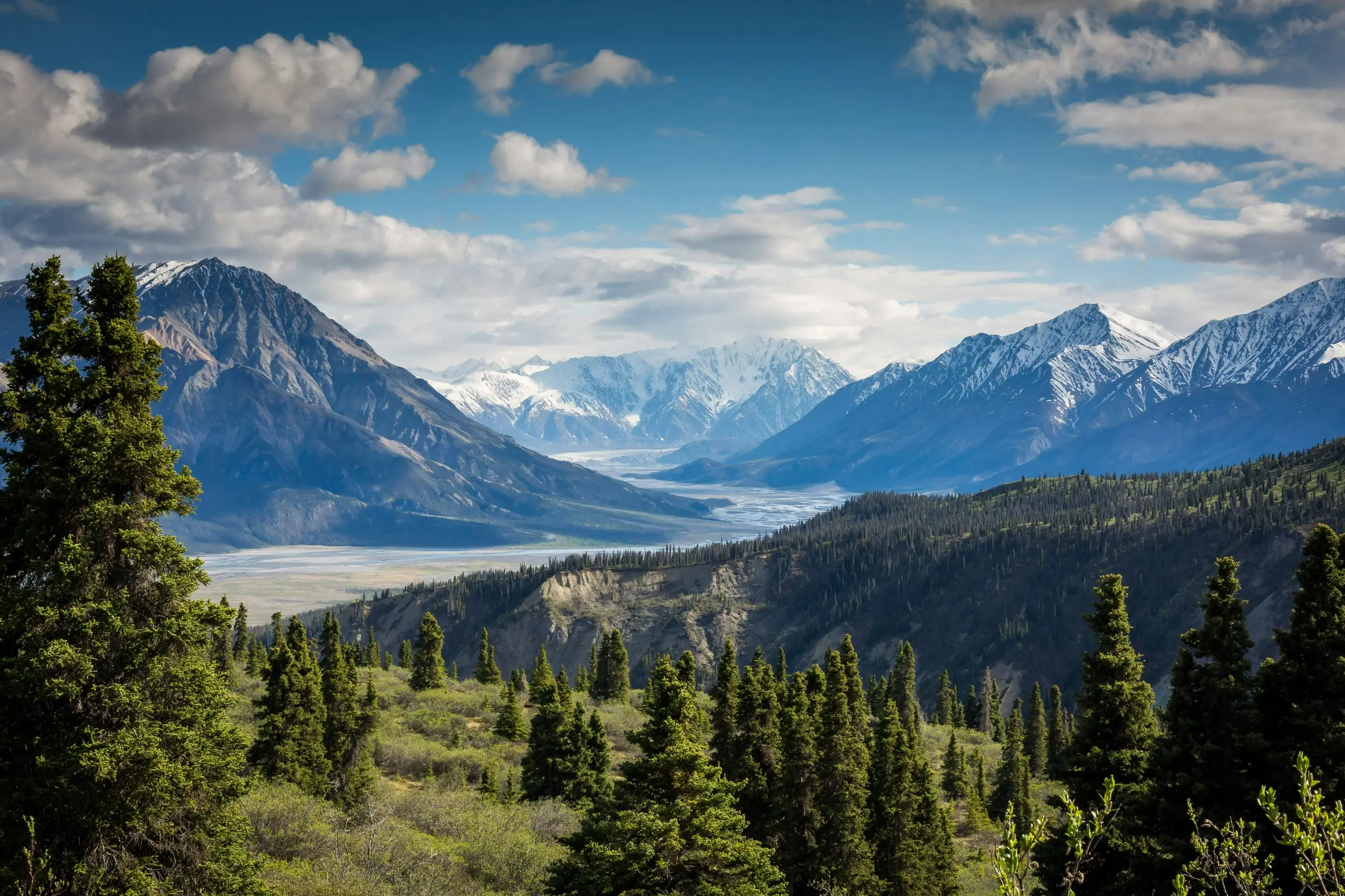 A glacial river valley running between snow-covered mountain ranges